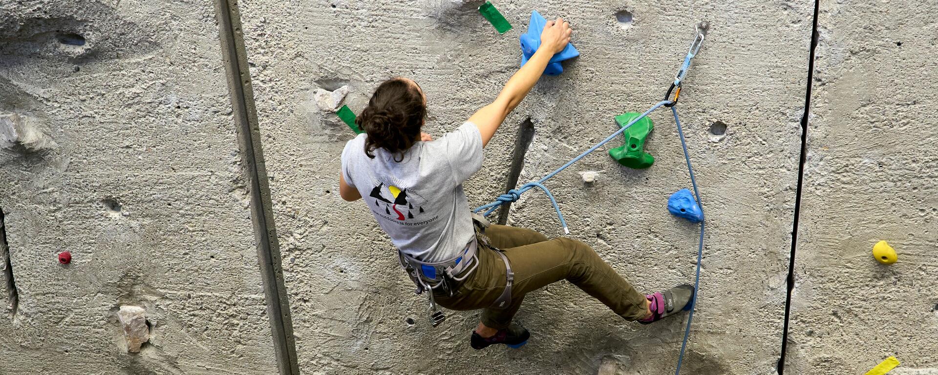 climber leads up concrete wall with rock and plastic holds