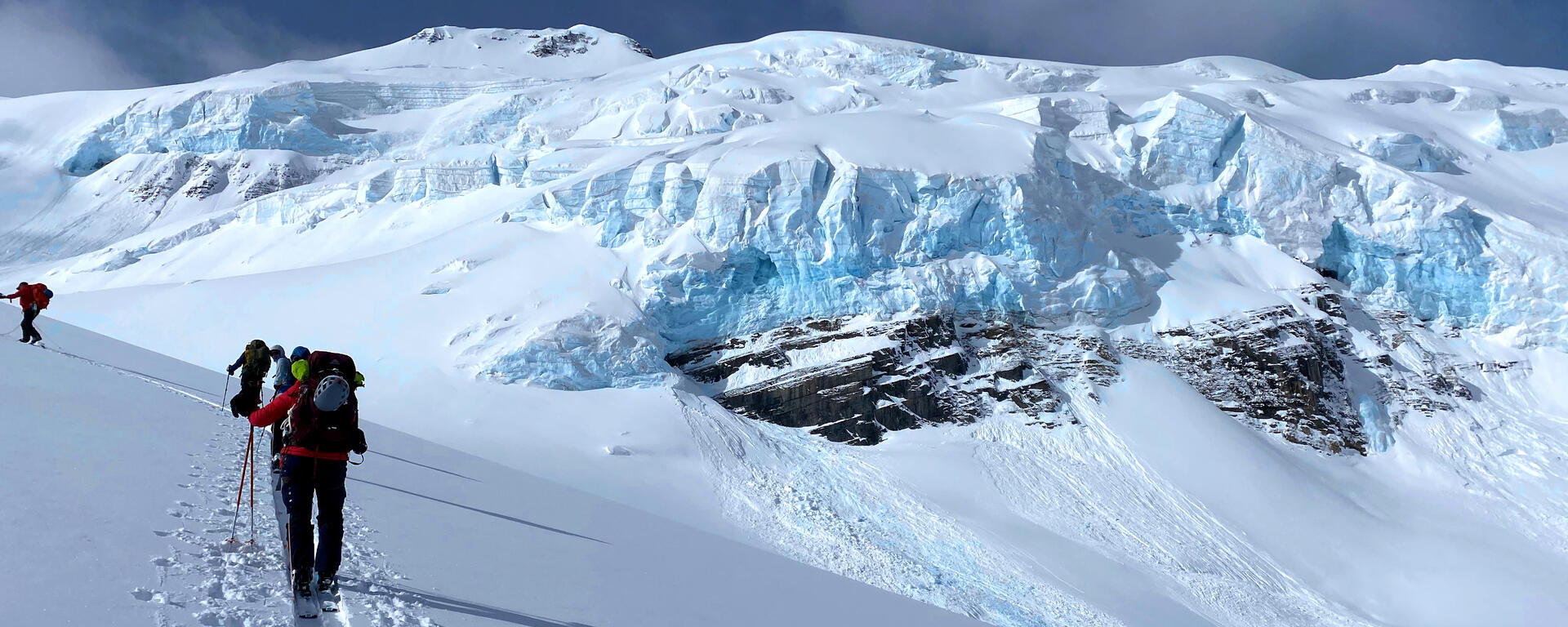 Backcountry skiers hiking in front of glacier