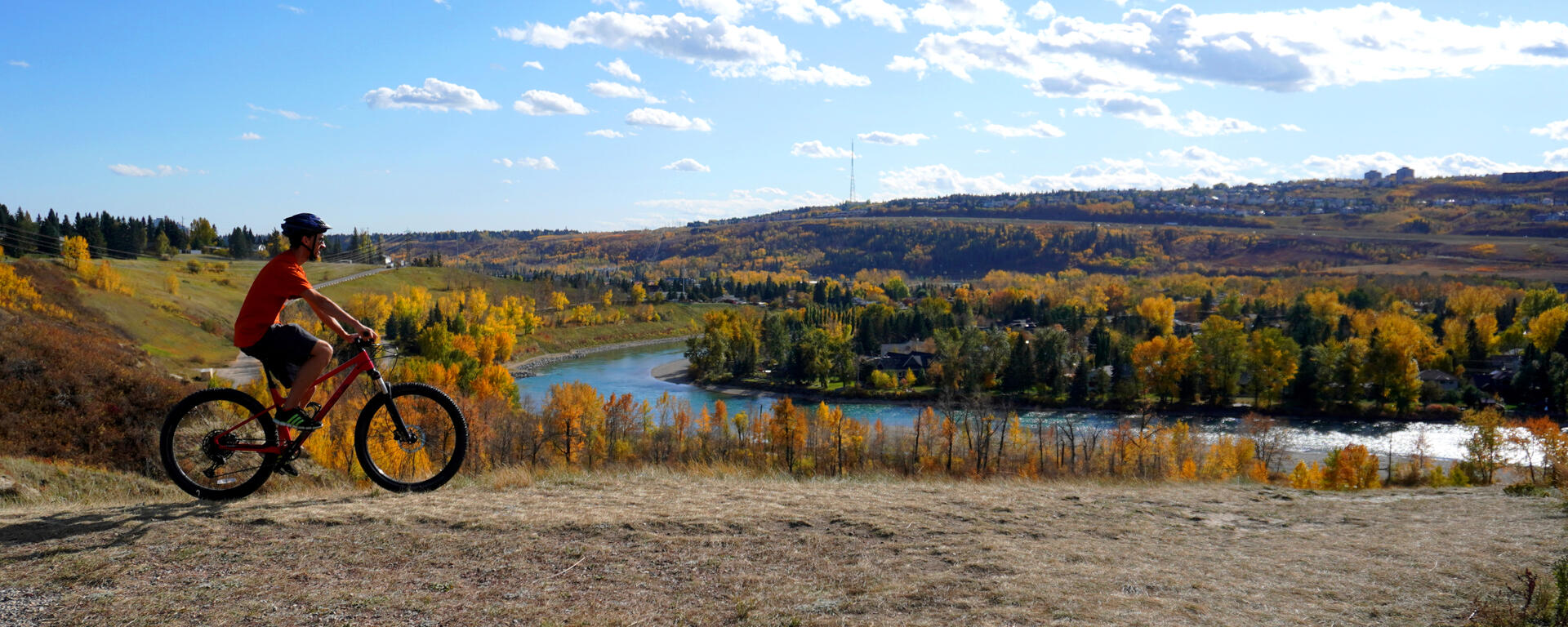 cyclist rides above fall-coloured river valley
