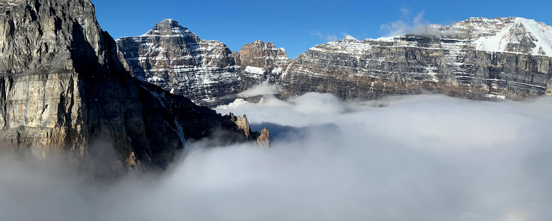 clouds fill valley below mountain peaks