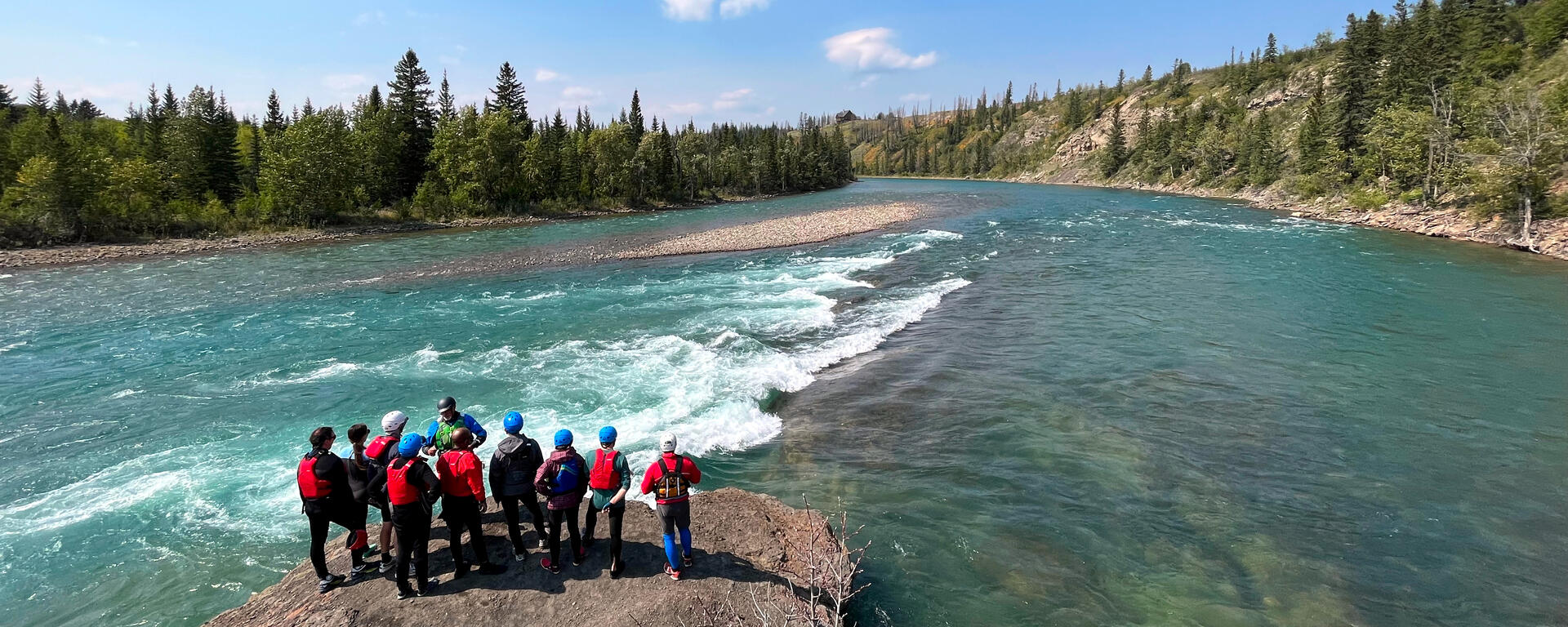 paddlers assess river wave from shore