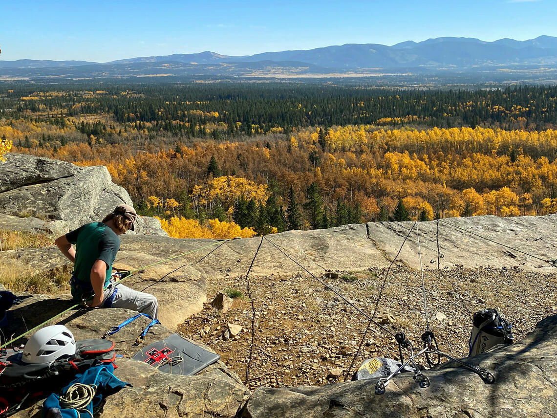 two people look at ropes rigged beyond the edge of a cliff