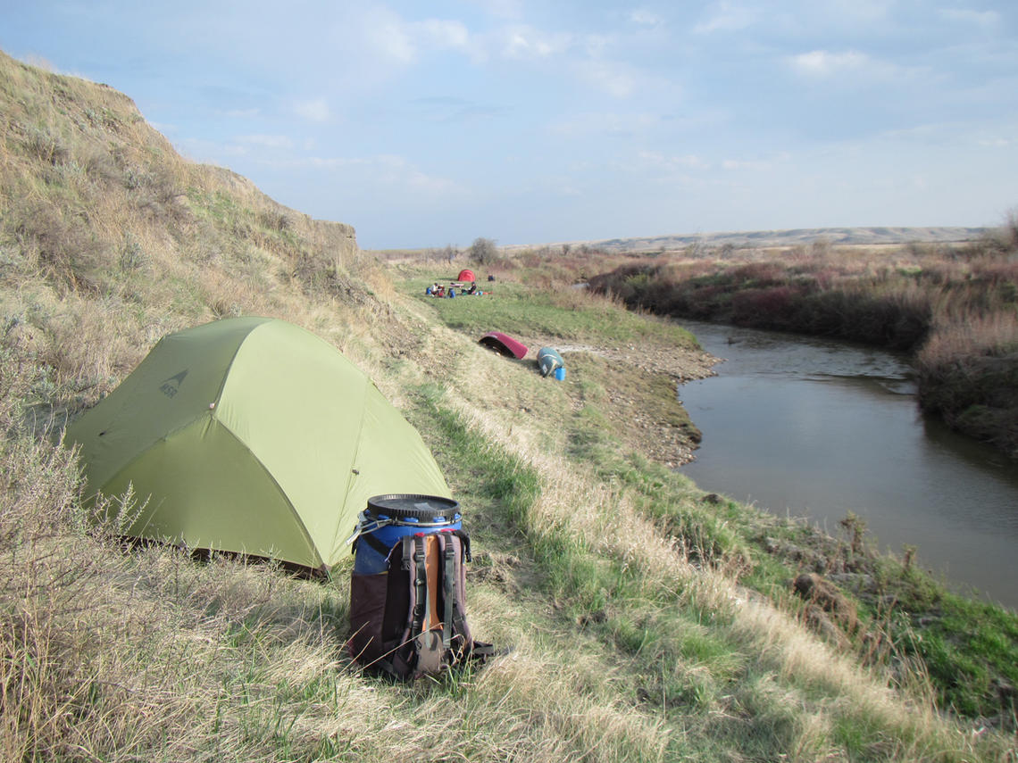 tent and canoe barrels on prairie