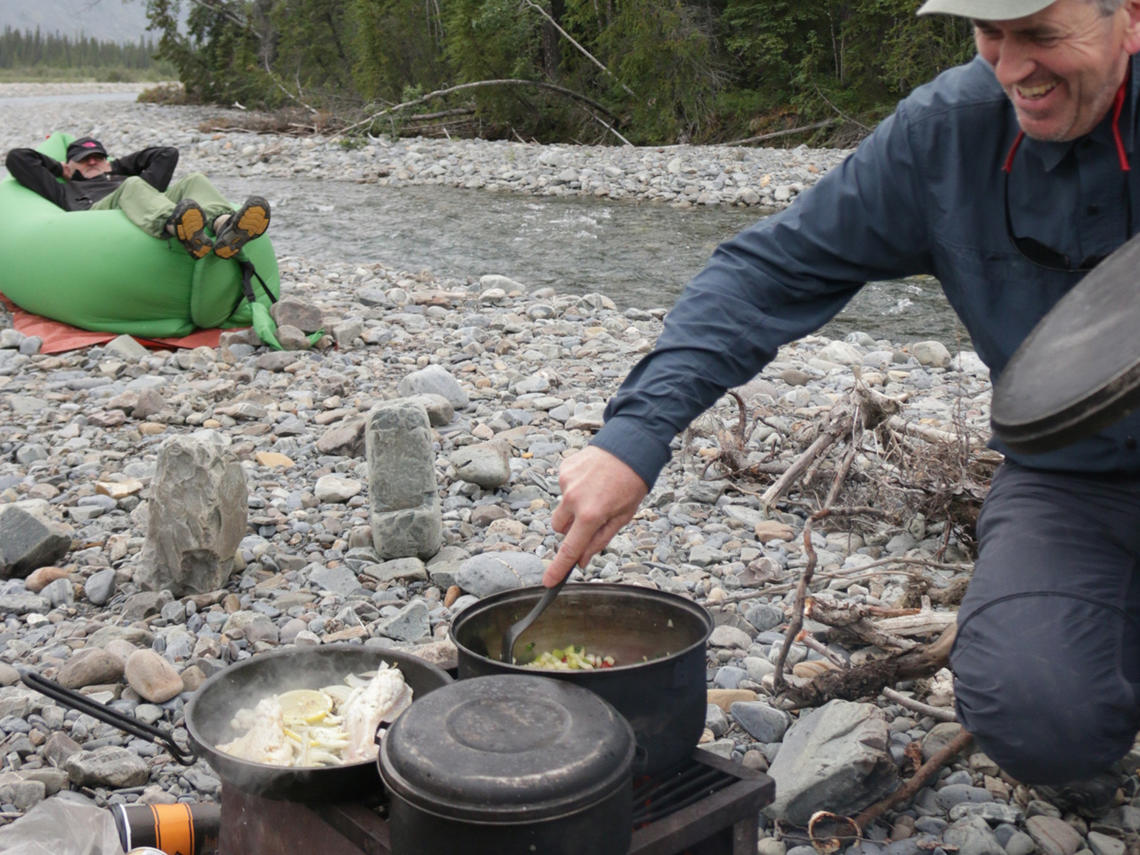 Backcountry cooking Paddler stirring backcountry meal on the banks of a river