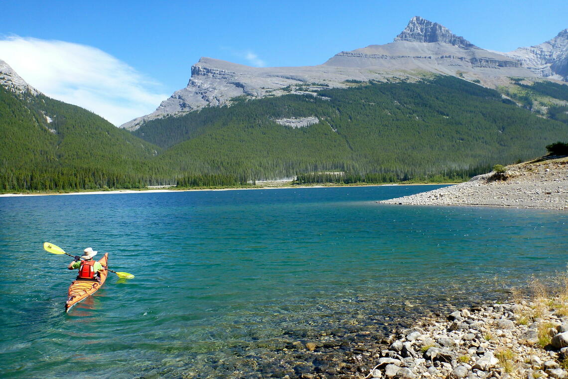 sea kayaker on lake with mountains beyond