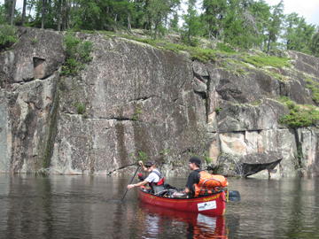 canoe beneath rock wall