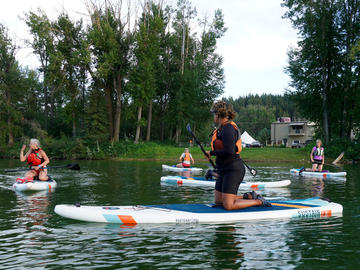 paddlers kneel on boards on flat water