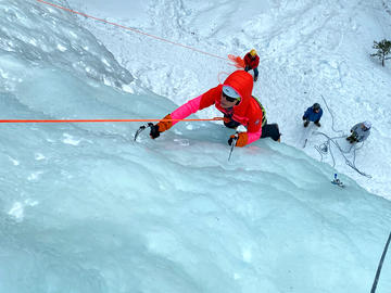 climber ascends ice on toprope