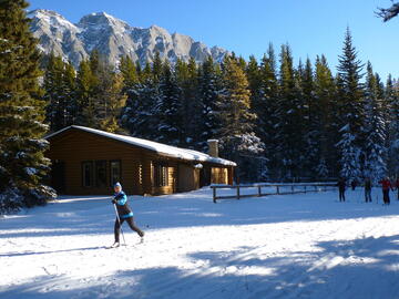 skier on groomed grid in front of hut