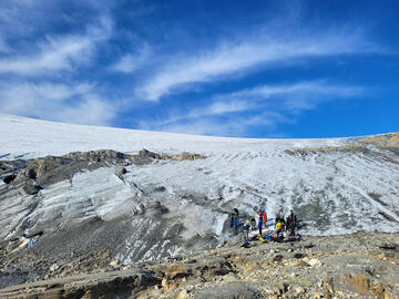 group of people stand at the base of glacier