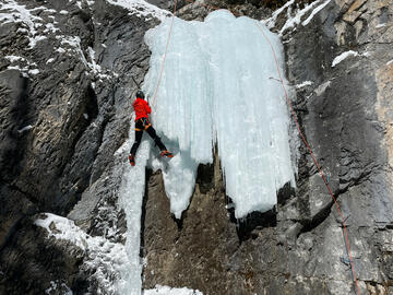climber ascends ice over narrow pillar