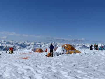 skis and tents are set up on snowpack overlooking mountain range