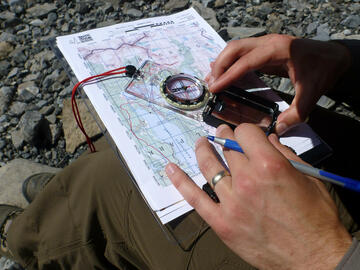 hands drawing on map with compass