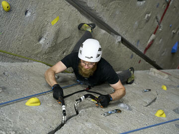 climber ascends wall using ice tools