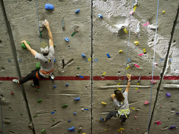 Two climbers ascend wall on top-rope