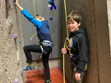 child belays while other child starts to climb