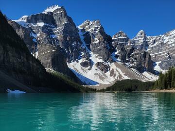SUP on turquoise lake with mountains behind
