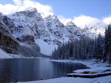 snowy mountains behind dark lake