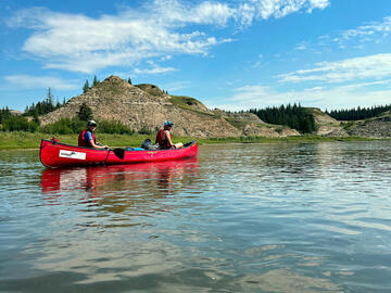 canoe on calm river water with hills behind