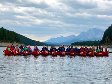 line of canoes on lake with mountains in view behind