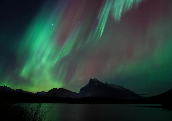 coloured bands of aurora wave over Mount Rundle
