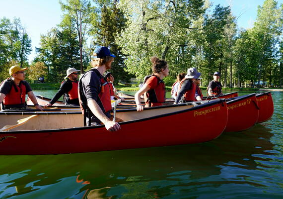several people in canoes listening to instructor