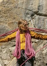 Sam coiling climbing rope in front of rock wall