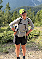 Brooke on trail with forested hills behind