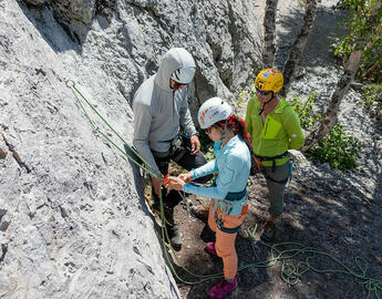 instructor setting up climbing gear for two lesson participants